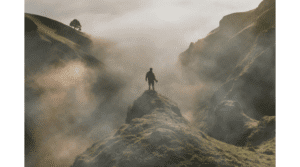 Pessoa no topo de uma montanha envolta em neblina, representando autoconhecimento, superação e novos caminhos comportamentais.
